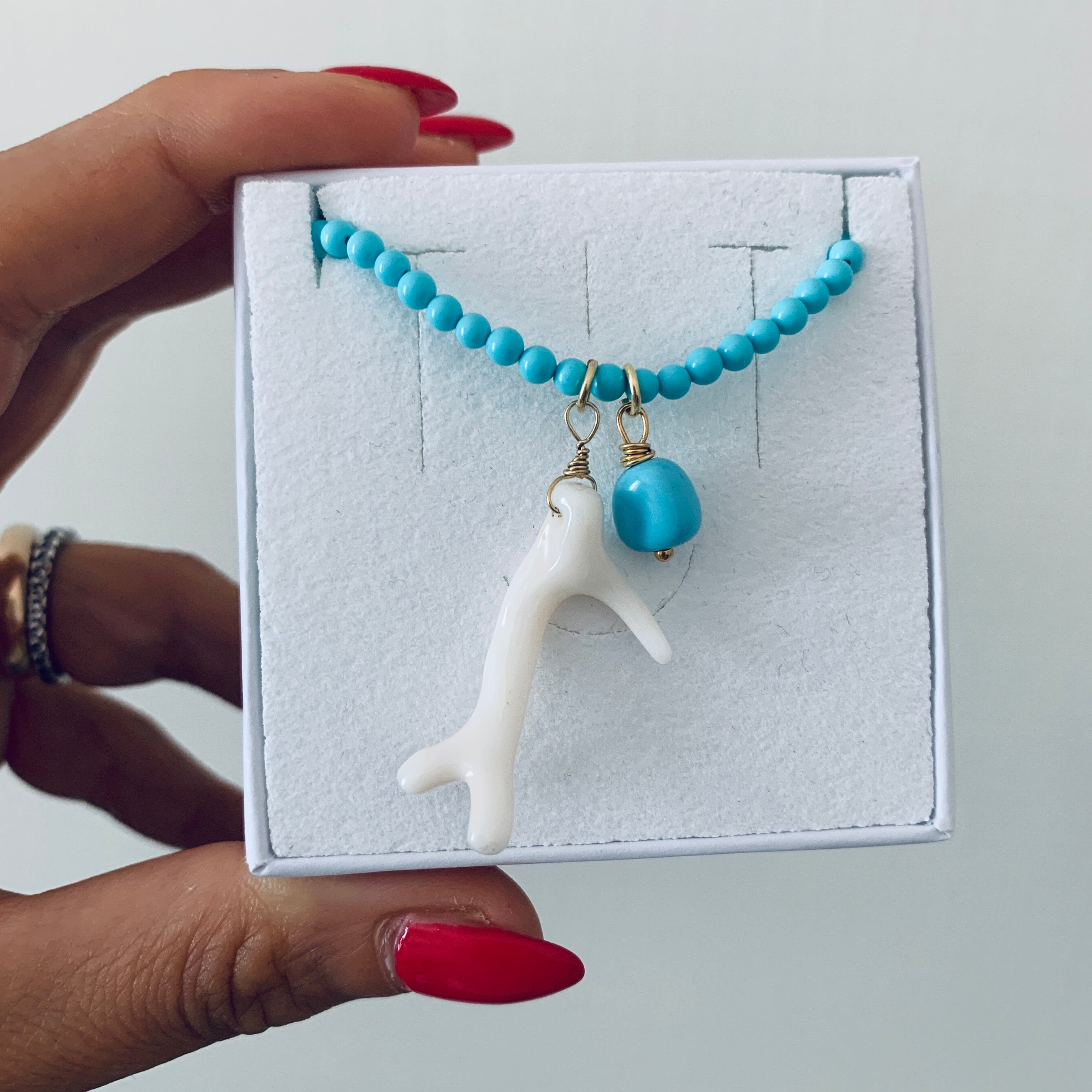 RabiosaJewels. Collana Borea Turchese con perline in pasta di turchese e due ciondoli: un ramo di corallo bianco naturale e una pepita di turchese. argento 925 bagnato oro giallo. foto in scatolino