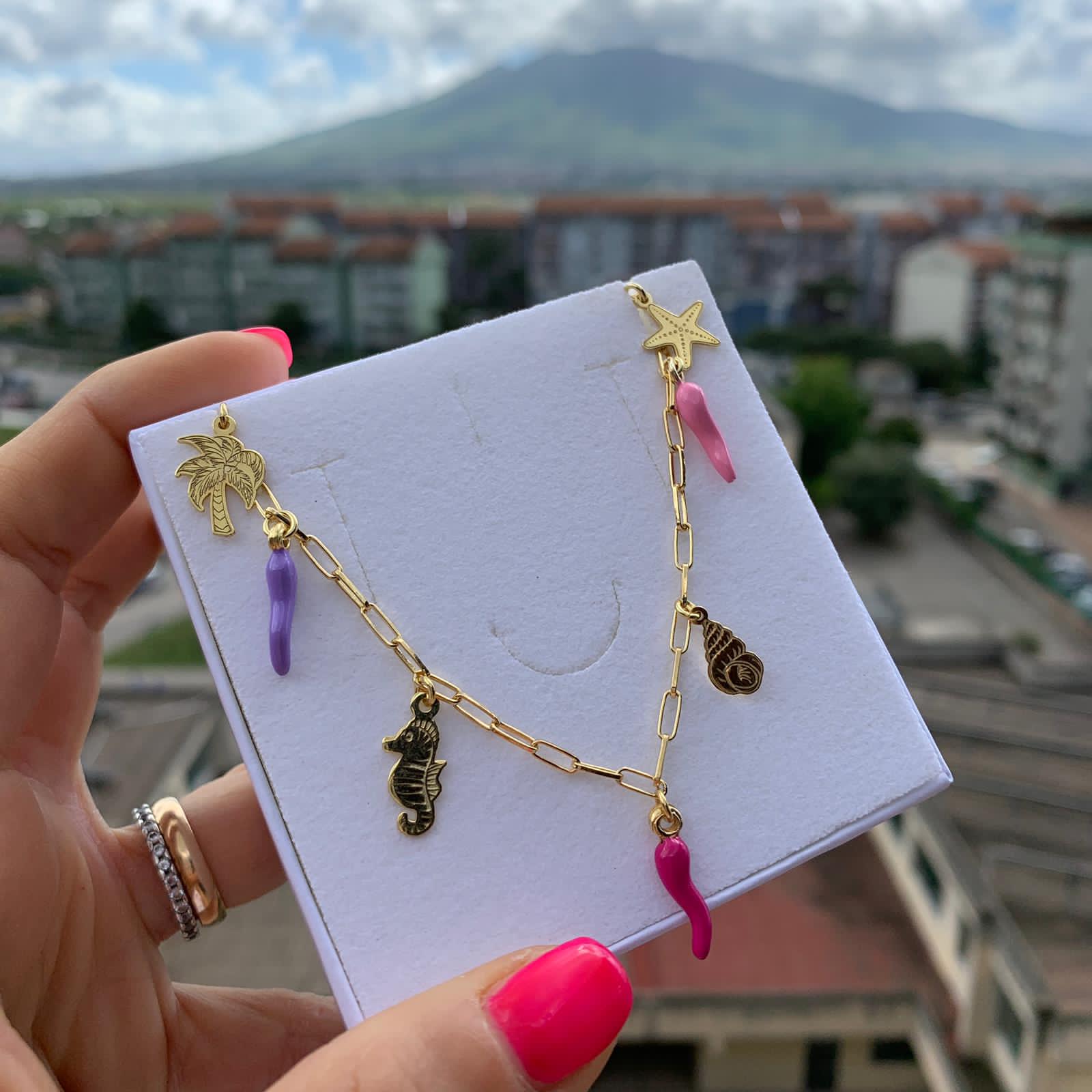 rabiosajewels. collana marina. collana in argento 925 gold con ciondoli marini e cornetti colorati nelle tonalità pastello del rosa. ciondolo cavalluccio marino. ciondolo palma. ciondolo conchiglia. ciondolo stella marina. cornetti portafortuna colorati